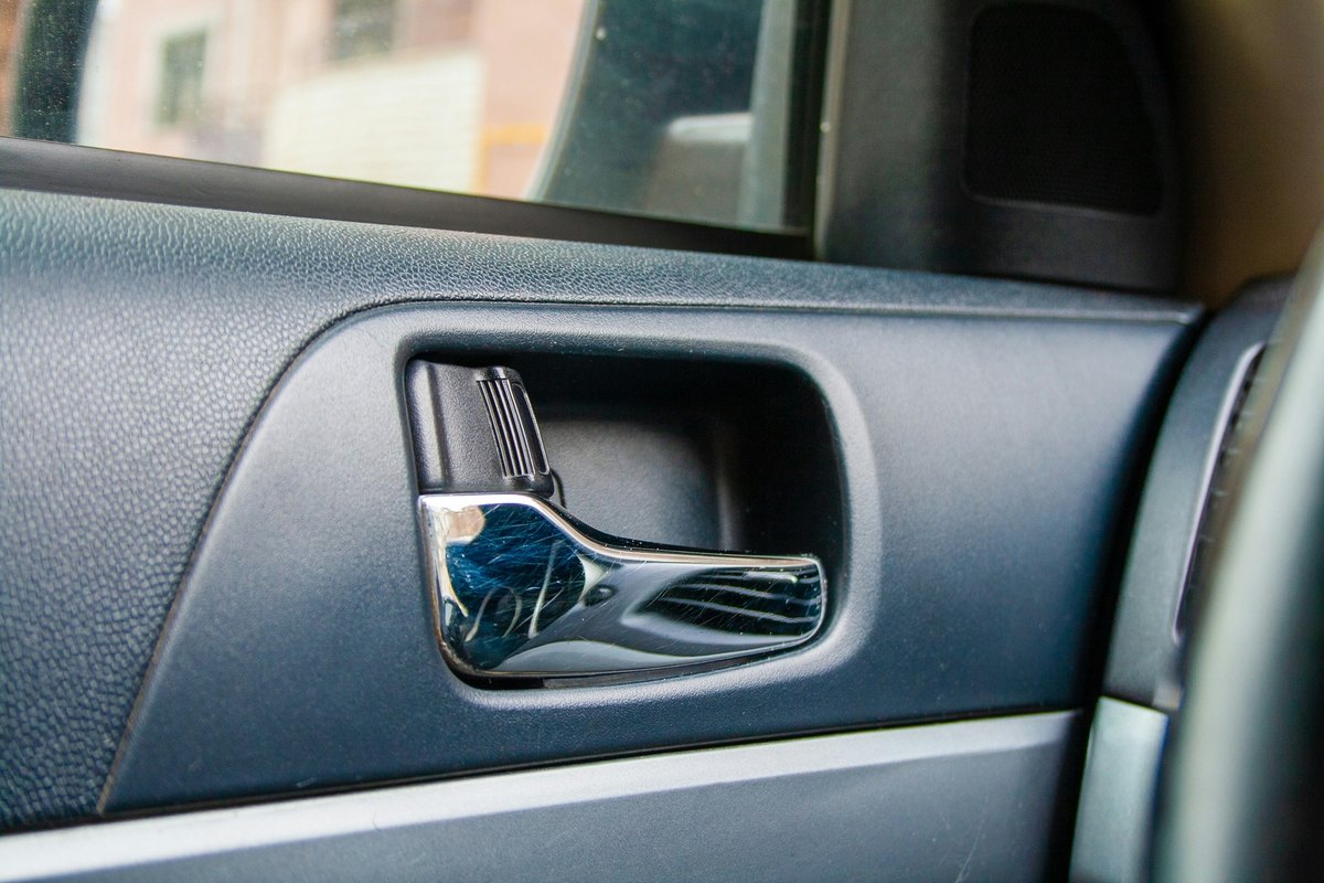 Chrome inside door handle in a dark blue-gray textured door panel