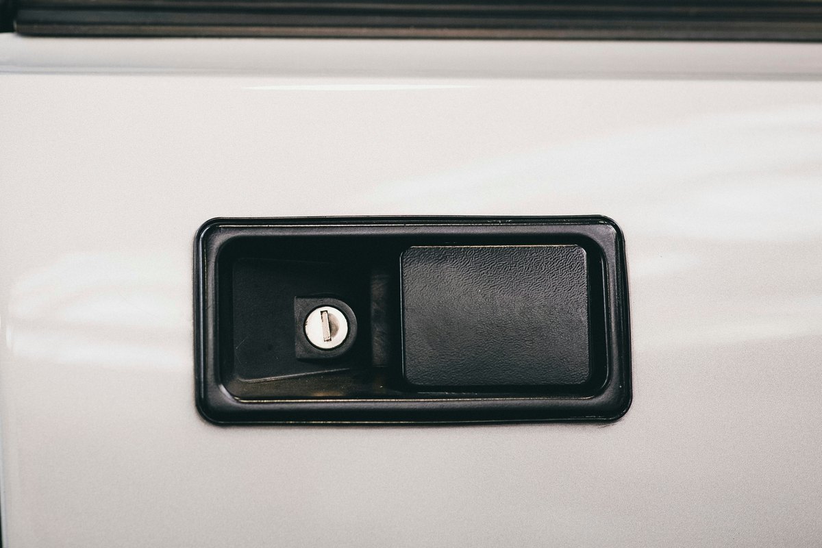Black recessed outside door handle with a key cylinder on a white vehicle door