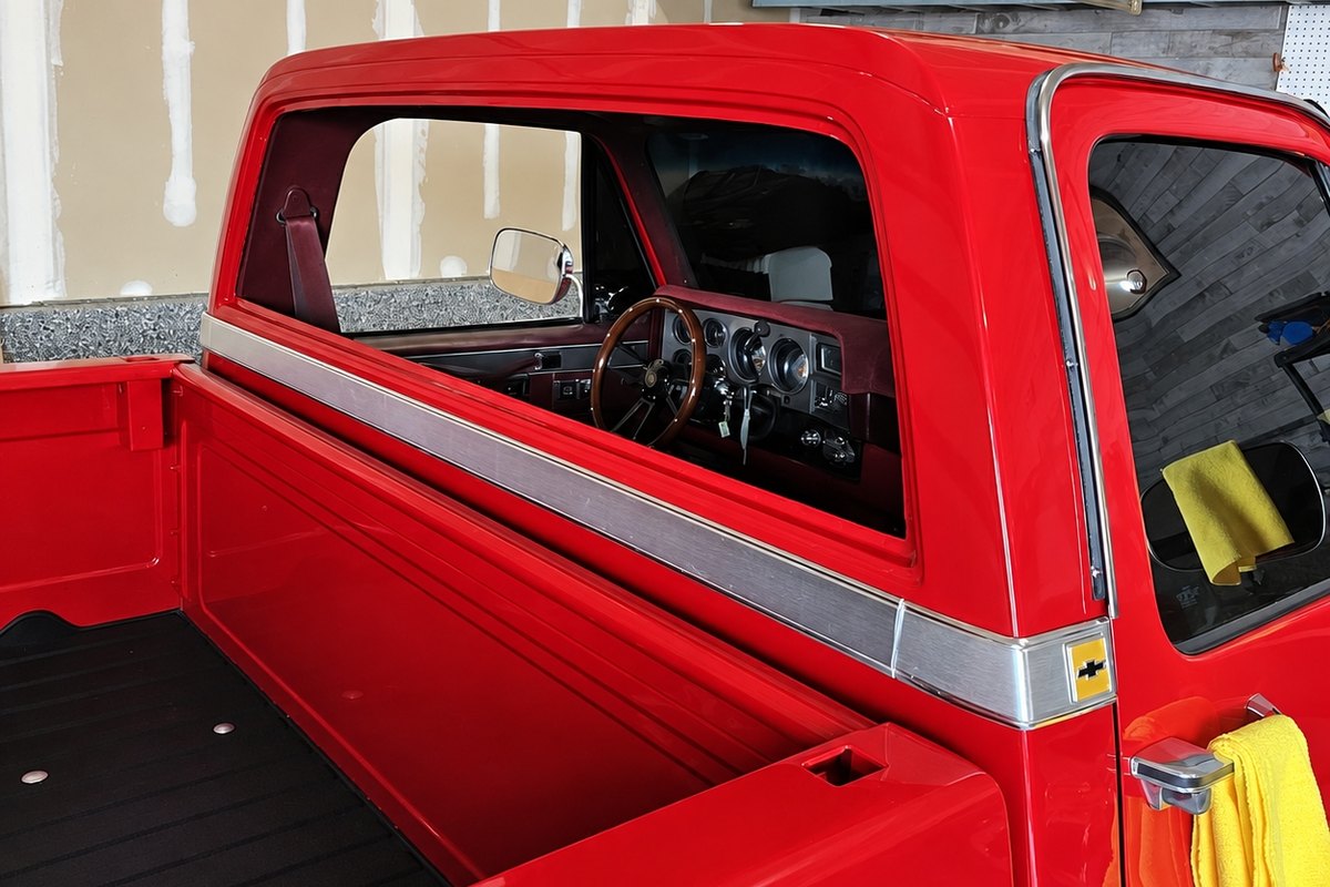 Red classic Chevrolet pickup with its cab back window out, seen from the bed