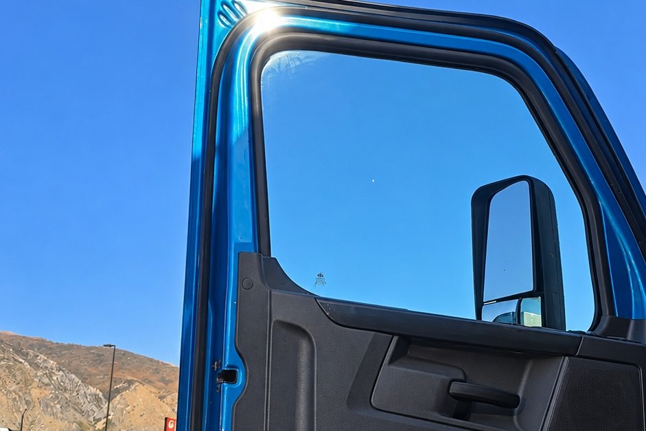 Blue semi truck door standing open with its new door glass in place