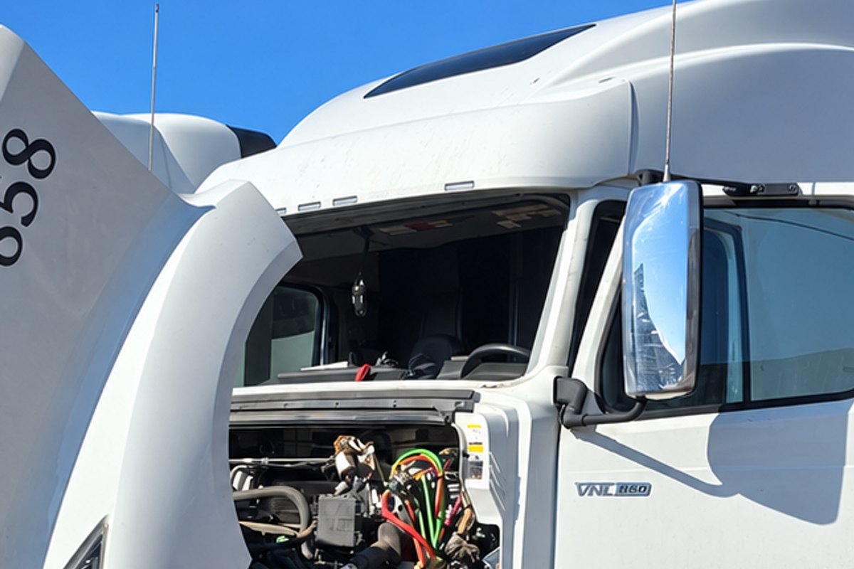 White Volvo sleeper truck with its hood tilted forward and its windshield out