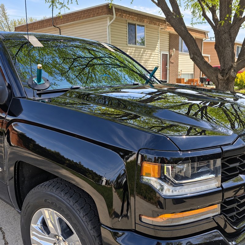 Black Chevrolet Silverado with its newly set windshield still carrying suction-cup handles