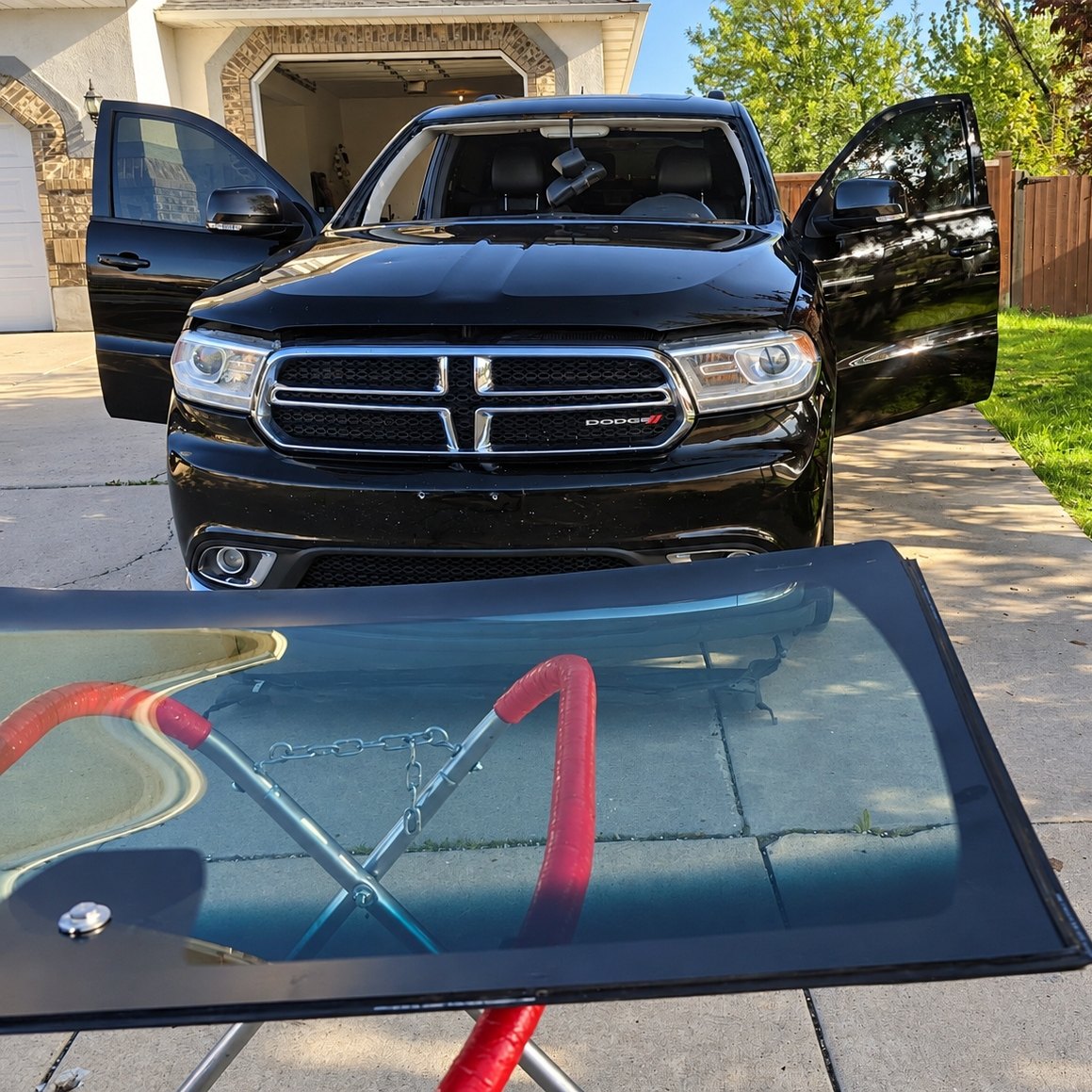 Black Dodge Durango in a driveway with its windshield removed and doors open