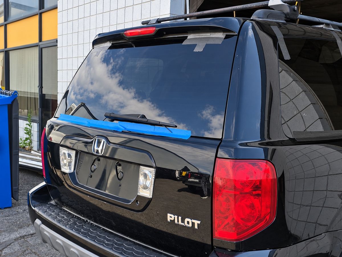 Black Honda Pilot with newly fitted back glass held by blue tape along the bottom