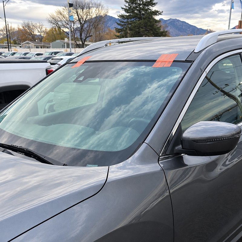 Gray SUV on a car lot with its newly fitted windshield held by orange tape